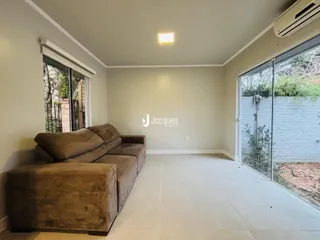 Sala de estar com sofá marrom e piso claro em imóvel no Brasil.