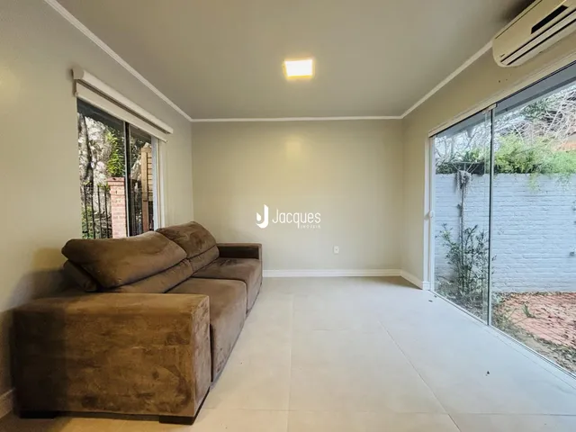 Sala de estar com sofá marrom e piso claro em imóvel no Brasil.