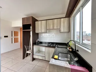 Cozinha com armários de madeira e bancadas escuras em Lajeado.