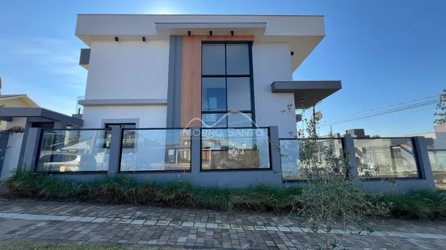 Fachada moderna de uma residência branca com grandes janelas de vidro.