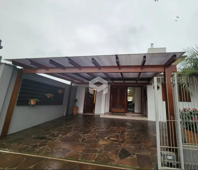 Fachada de uma residência com área coberta e piso de pedra.