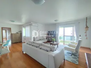 Sala de estar com sofá branco e piso de madeira clara.
