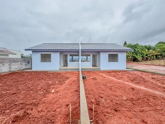 Vista externa de uma casa em terreno com solo avermelhado.