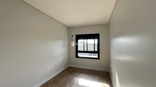 Hall de corredor com piso de madeira e janela no final.