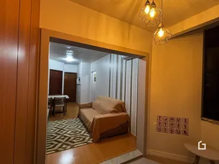 Sala de estar com sofá e piso de madeira na residência.