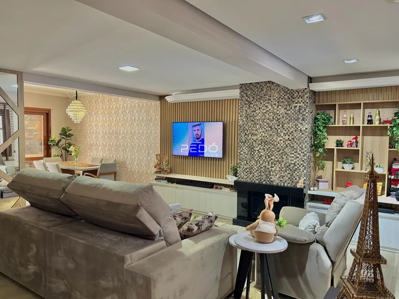 Sala de estar moderna com sofá grande e lareira em um imóvel no Brasil.