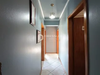 Vista de um corredor interno com paredes azuis e portas de madeira.