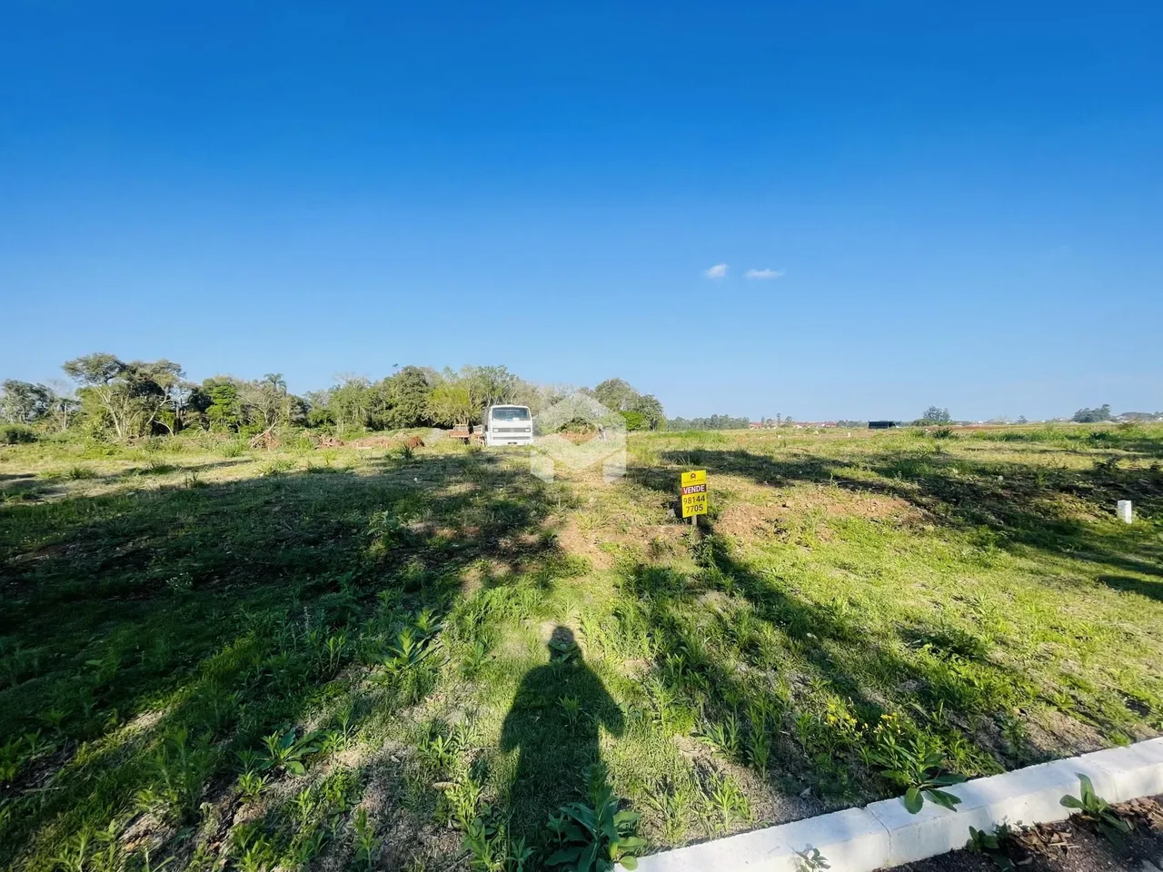 Vista de um campo gramado com vegetação no primeiro plano.