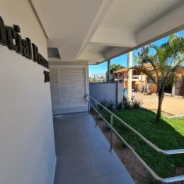 Vista externa de um terraço com grade de metal e vegetação.