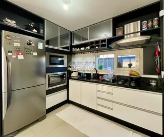 Interior de uma cozinha moderna com armários escuros e eletrodomésticos de aço inoxidável.