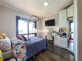 Quarto com cama e televisão em um apartamento com piso de madeira.