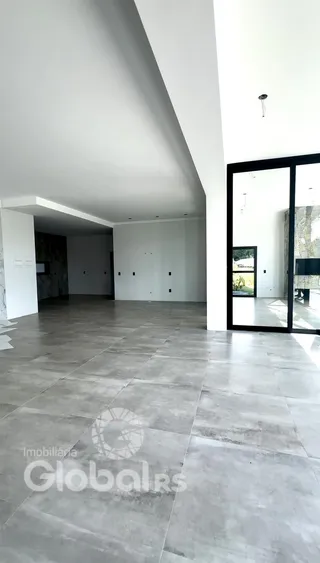 Espaço interno amplo com piso de cerâmica cinza e paredes brancas.