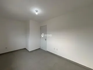 Ambiente interno de uma sala com paredes brancas e piso de cerâmica.