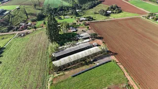 Vista aérea da propriedade mostrando campos agrícolas e estruturas no interior.