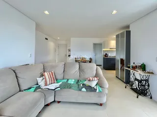 Sala de estar com um grande sofá cinza e paredes brancas.