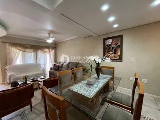 Sala de estar com sofá e mesa de jantar de vidro em um imóvel no Brasil.