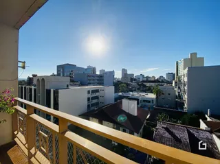 Vista de um terraço com grade de ferro sobre uma paisagem urbana.