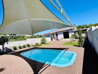 Vista externa de uma piscina com guarda-sol em um quintal.