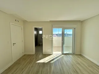 Interior de um ambiente com piso de madeira clara e porta de vidro abrindo para uma área externa.