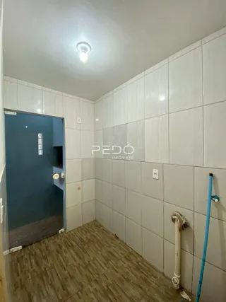 Interior de um corredor com piso de madeira e paredes brancas em Lajeado.