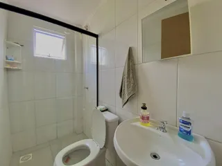 Foto interna de um banheiro com revestimento de azulejos brancos.