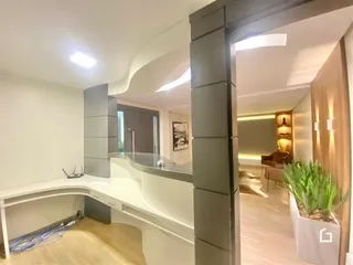 Interior de uma sala de estar moderna com piso de madeira clara e iluminação embutida.