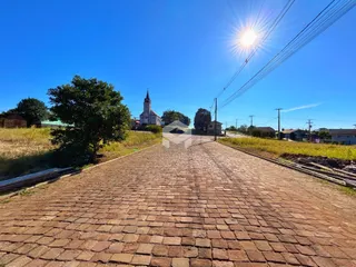 Uma rua pavimentada de tijolos leva a uma igreja no horizonte sob um céu azul.