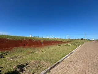 Paisagem de terra vermelha e grama verde sob um céu azul claro.