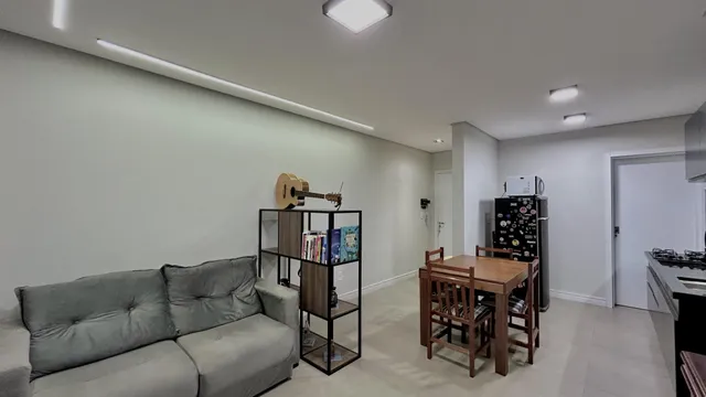 Uma sala de estar com sofá cinza e um conjunto de jantar de madeira.