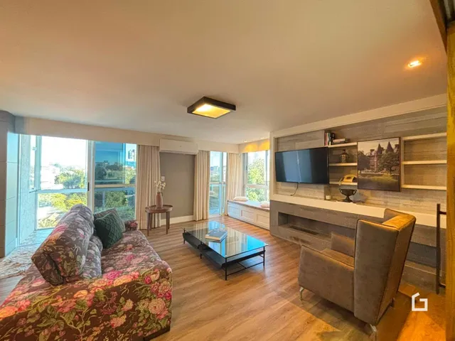 Sala de estar com piso de madeira e vista para o exterior.