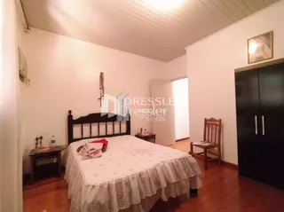 Quarto com cama de casal e piso de madeira em uma residência.