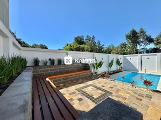 Foto da área externa com piscina e deck de pedra no imóvel.
