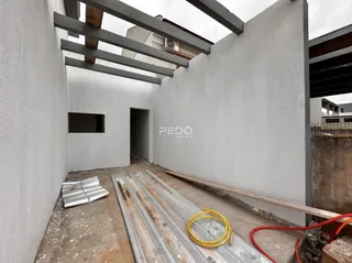 Vista interna de uma área com paredes brancas e vigas expostas.