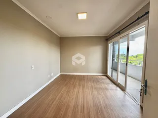 Sala de estar com piso de madeira e porta de vidro que dá para a varanda.