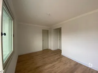 Uma sala com piso de madeira clara e paredes brancas.