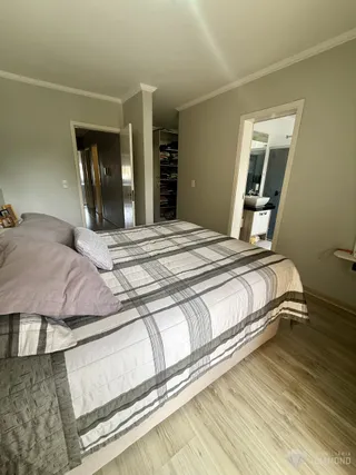 Quarto com cama e portas de acesso a outros cômodos.