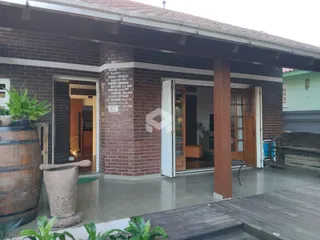 Fachada de uma residência com alvenaria de tijolos aparentes e área externa coberta.
