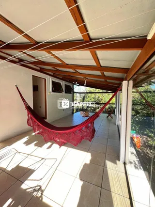 Área externa coberta com um balanço vermelho e piso de cerâmica.