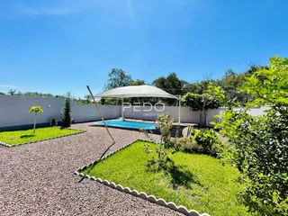 Vista externa de uma área de lazer com piscina e jardim.