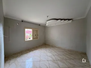 Interior de uma sala com piso de cerâmica clara e paredes brancas.