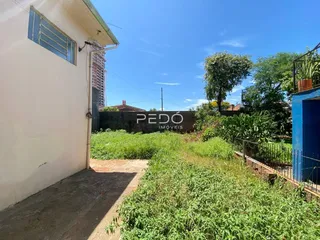 Vista da fachada de uma residência com vegetação densa no primeiro plano.