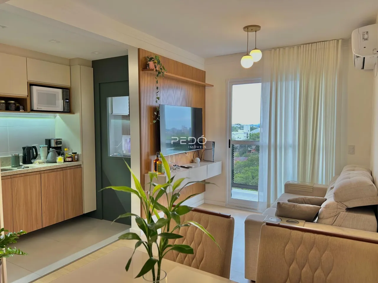 Sala de estar com cozinha integrada e vista para o exterior.