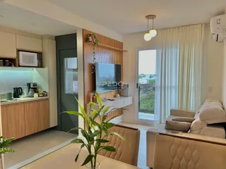 Sala de estar com cozinha integrada e vista para o exterior.