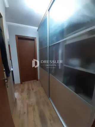 Hall de entrada com porta de madeira e piso de madeira clara.
