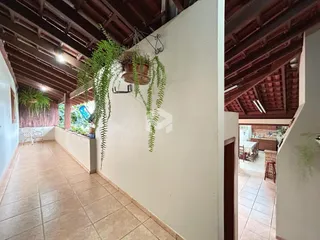 Corredor interno com piso de cerâmica e vigas de madeira expostas.