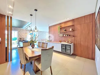 Sala de jantar moderna com mesa de madeira e iluminação pendente.