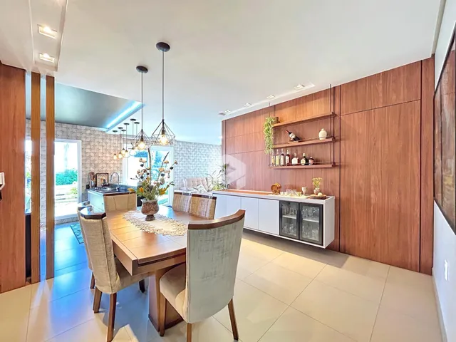 Sala de jantar moderna com mesa de madeira e iluminação pendente.