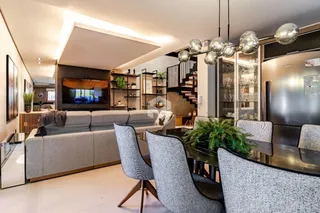 Sala de estar moderna com sofá e mesa de jantar em um apartamento no Brasil.