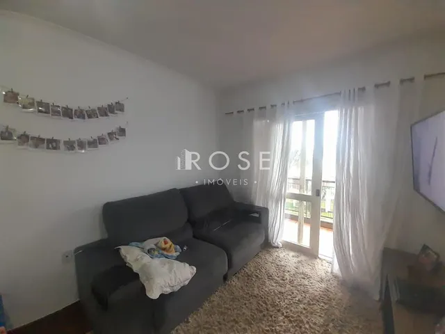 Sala de estar com sofá cinza e piso de carpete.