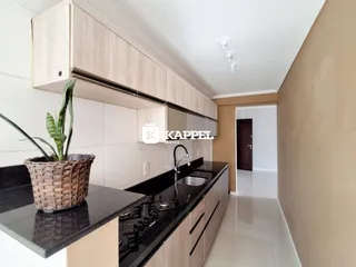 Cozinha moderna com armários claros e bancada escura.